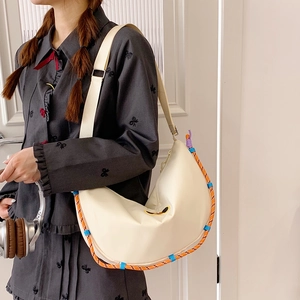 Dettaglio della borsa a mezzaluna bianco sporco con accenti di corda intrecciata colorata