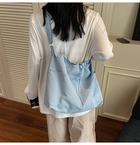 Light blue waffle textured tote bag worn over the shoulder showing back view on a model