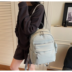Detailed view of grey blue backpack with lychee grain texture and silver ring zippers