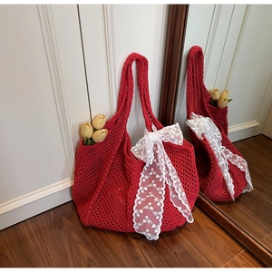 Gros plan d'un sac cabas au crochet rouge avec un nœud en dentelle blanche sur maille