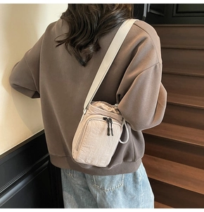 Detailed back view of mini nylon drawstring bucket bag in beige on model shoulder