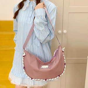 Dettaglio della borsa a spalla a mezzaluna in nylon rosa con patch cucciolo e corda