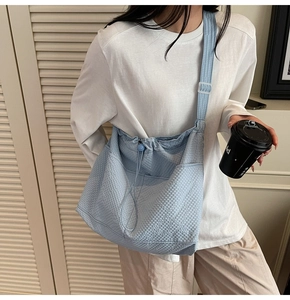 Detail of light blue pleated nylon tote bag with drawstring closure and wide shoulder strap