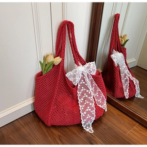 Détail d'un sac cabas en crochet rouge avec un élégant nœud en dentelle blanche et des fleurs