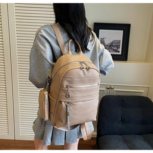 Detail of camel leather backpack showing pebble texture and detachable coin purse accessory