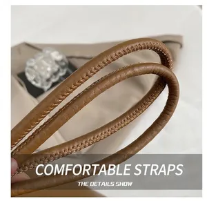Detail showing high-quality brown leather shoulder strap with reinforced stitching on tote bag
