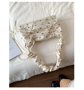 Détail du sac à bandoulière floral avec motifs de nœuds rouges et bandoulière plissée
