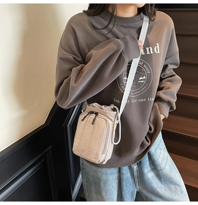 Detail shot of the nylon drawstring crossbody bag worn by a model in casual street style