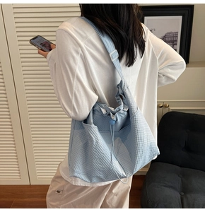 Detail showing light blue checkered tote bag with drawstring closure and adjustable strap