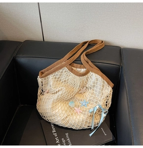Detail of beige woven tote bag with star charms and ribbon on a black sofa