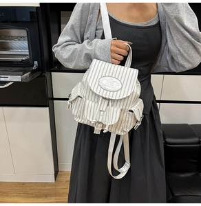 Detailansicht eines gestreiften Canvas-Rucksacks mit Kordelzug und silbernem Markenlogo