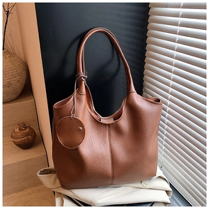 Gros plan sur le cuir grainé marron et la pochette ronde amovible du sac cabas