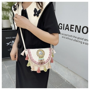 Dettaglio della borsa in paglia intrecciata con ricami etnici e ciondoli a nappe colorate