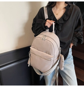 Detail of beige faux leather backpack with round pouch charm and patterned wide strap