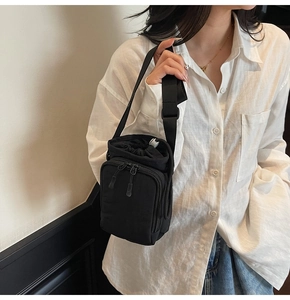 Detailed view of black nylon mini crossbody bag with drawstring closure and dual zip pockets