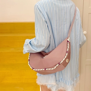 Dettaglio borsa a mezzaluna malva con corda intrecciata e tracolla sportiva in nylon