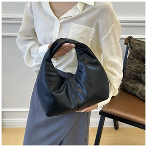 Detalle del bolso hobo negro que muestra la textura del cuero y los pliegues elegantes