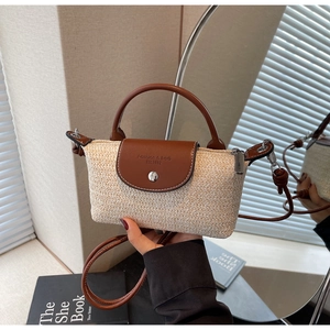 Close-up of woven straw handbag with brown leather flap and embossed fashion logo