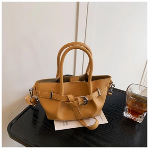 Gros plan du sac cabas en cuir gingembre avec boucle sur une table en bois
