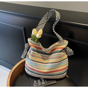 Dettaglio di borsa tote in paglia a righe colorate con trama intrecciata e tracolla larga