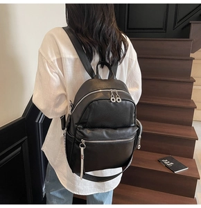 Detail of black lychee grain leather backpack featuring modern silver ring zippers