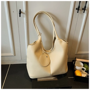 Vue détaillée de la texture du cuir grainé crème sur le sac cabas avec bandoulière