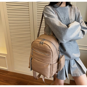 Detail view of beige leather backpack with side pockets and a small round pouch attachment