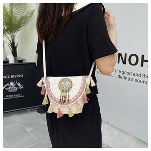 Dettaglio borsa boho in paglia intrecciata con nappe colorate e ricamo mandala