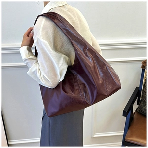 Dunkelrote Leder-Einkaufstasche am Model mit geräumiger Halbmond-Silhouette gestylt
