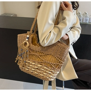 Close-up of woven straw tote bag featuring wavy patterns and blue decorative tassels