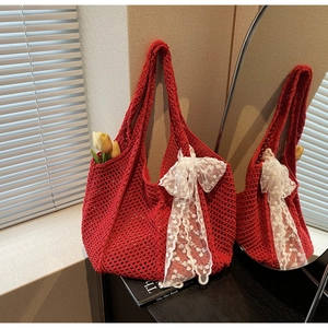 Sac fourre-tout en maille rouge avec nœud en dentelle blanche reflété dans un miroir chic