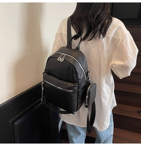 Detail of black lychee grain leather backpack with detachable coin purse and silver zippers