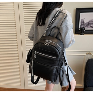 Detail of black pebbled leather backpack with patterned straps and sequin charm