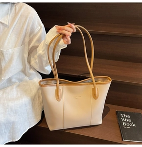 Minimalist beige tote bag with brown straps shown on wooden stairs in a lifestyle setting