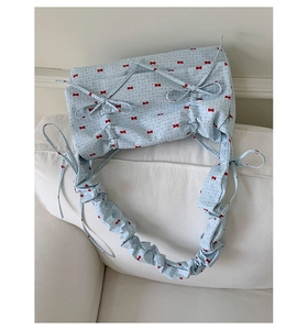 Gros plan du sac bleu clair avec motifs nœuds rouges et détails de bandoulière froncée
