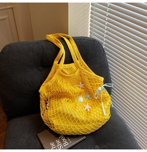 Detail of woven yellow mesh tote bag with colorful starfish decor and blue ribbon bow