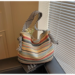 Dettaglio macro della borsa tote in paglia intrecciata multicolore con tracolla a righe