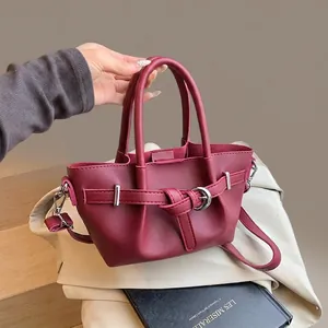 Détail du sac seau bordeaux en cuir texturé avec boucle argentée et bandoulière amovible