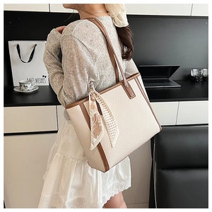 Beige tote bag with brown leather trim and silk scarf shown in an office setting