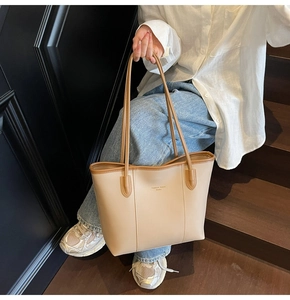 Detail of a large beige tote bag with brown straps and textured PU leather finish