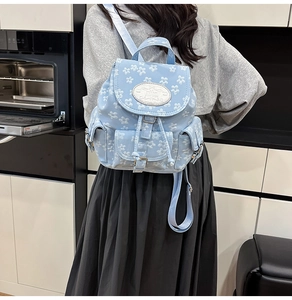 Detaillierte Seitenansicht eines hellblauen Rucksacks mit Blumenmuster und Taschen