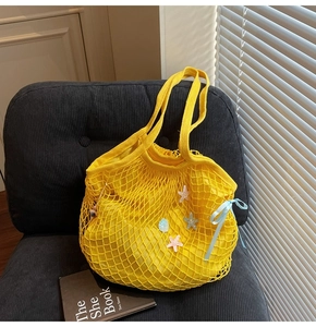 Detailed close-up of yellow mesh tote bag with sequin stars and light blue ribbon