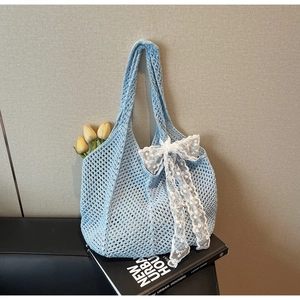 Gros plan détaillé du sac crochet bleu clair avec nœud dentelle sur un livre d'art