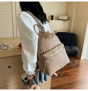 Chic beige pebbled leather backpack with patterned straps on model in casual setting