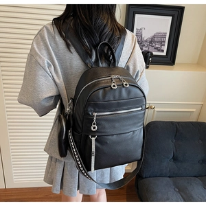 Close-up of black lychee grain leather backpack with multiple zippers and geometric straps