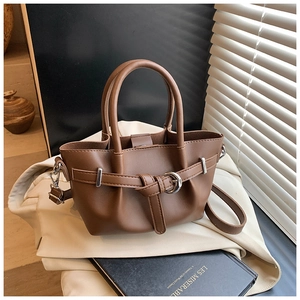 Gros plan sac à main en cuir marron avec boucle anneau argenté sur fond beige