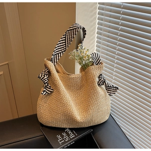 Dettaglio di una borsa tote in paglia intrecciata beige con spalline a righe bianche e nere
