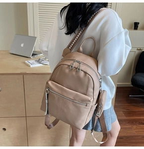 Detail view of khaki pebbled leather backpack with patterned straps and mini coin purse