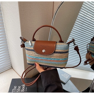 Close-up of woven striped straw mini bag with brown leather flap and metal chain strap