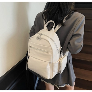 Detail view of cream backpack with litchi texture and a detachable mini circular pouch